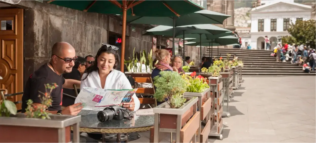 Two travelers study a map as they relax at a café in Quito’s Historic Center, planning their next adventure.