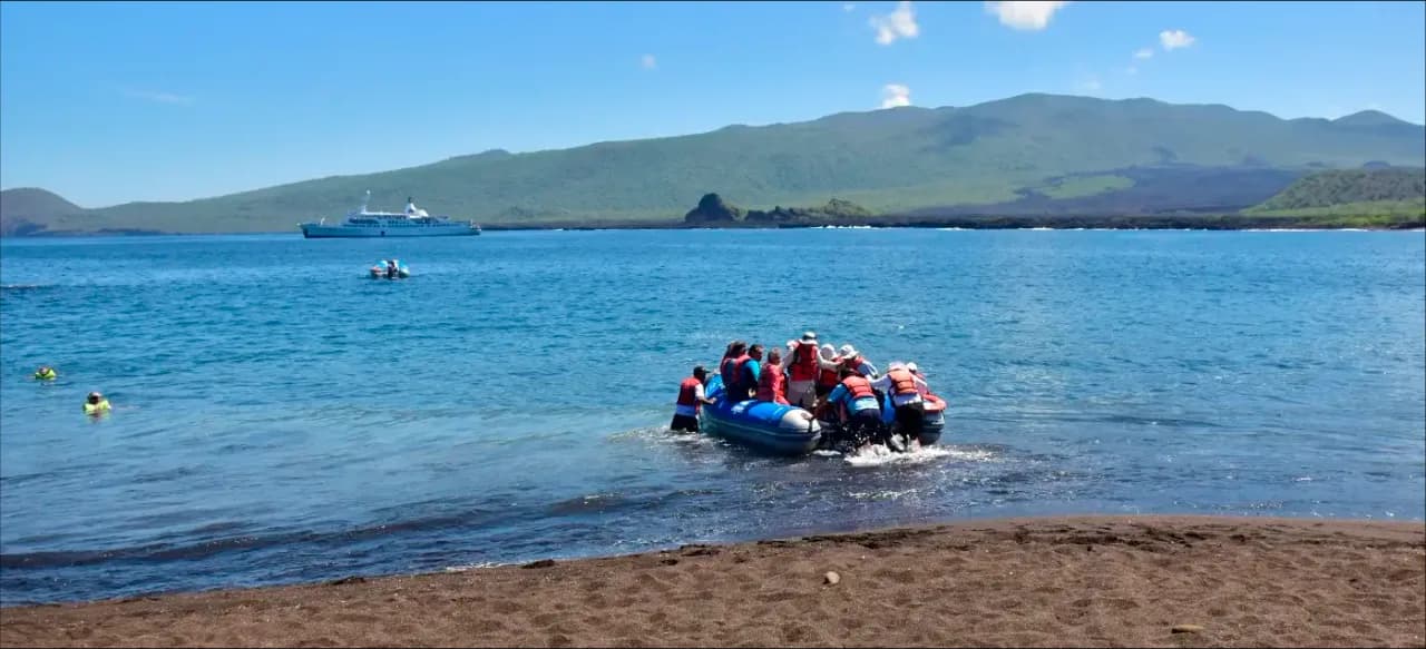 Travelers inside a panga, with the Galapagos Legend Boutique Expedition Cruise in the background.