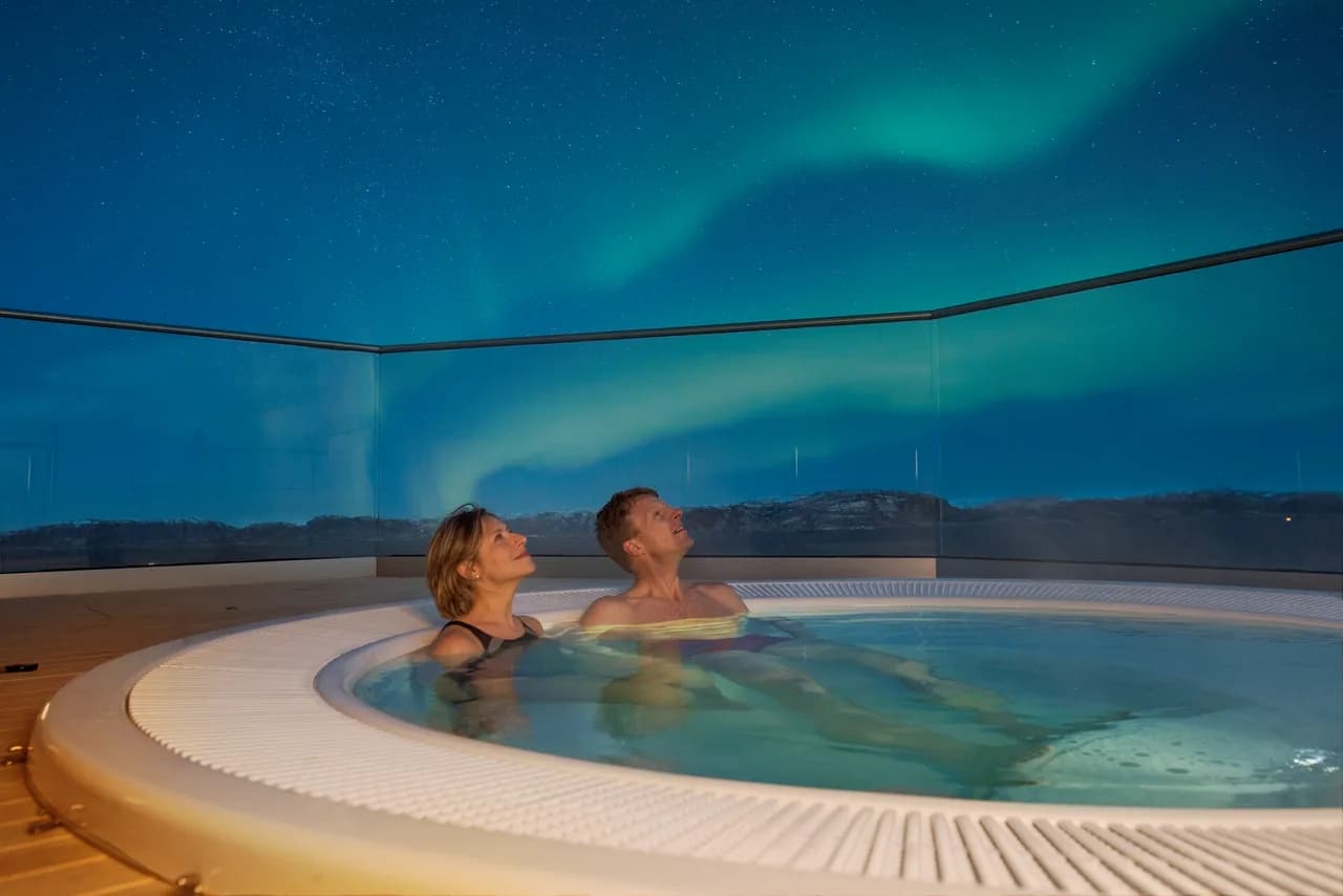 Northern Lights above a hot tub on deck on a Hurtigruten cruise in Norway