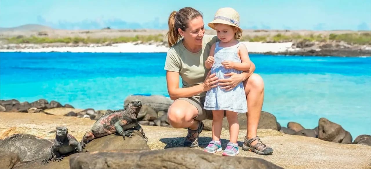 Mother and child observing marine iguanas on a rocky beach in the Galapagos Islands during a family wildlife tour.