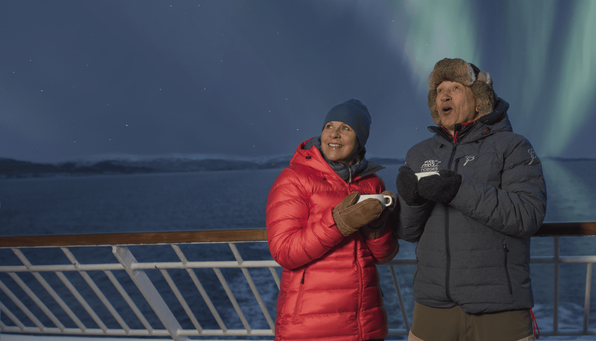 Passengers aboard a Hurtigruten Ship gaze at the Northern Lights at night